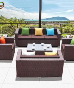 Bàn Ghế Sofa Mây Nhựa MN012 với sofa góc tông nâu đỏ, đệm trắng và bàn trà sáng